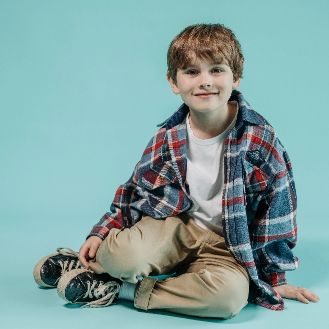 young boy sitting against blue background